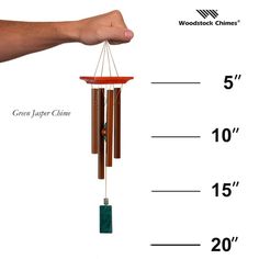 a hand holding a wooden wind chime with the measurements for it's length