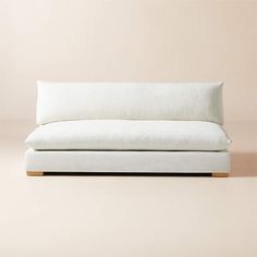 a white couch sitting on top of a wooden floor next to a beige wall in front of it