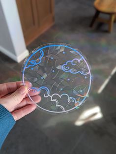 a person holding up a glass plate with clouds and stars on it