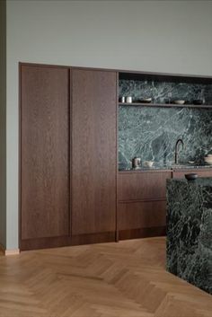 a kitchen with wooden cabinets and marble counter tops on the wall, along with an island