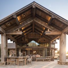 an outdoor dining area with tables and chairs under a wooden roof over looking the water