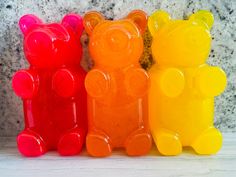 three gummy bears sitting next to each other on a marble counter top in different colors