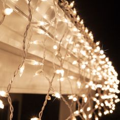 the lights are hanging on the side of the house in front of the window at night