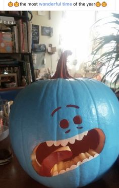 a blue pumpkin with an angry face on it's face and mouth, sitting on a table