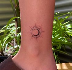 a woman's foot with a small sun and moon tattoo on the side of her leg