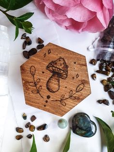 a wooden coaster with a mushroom on it surrounded by rocks, stones and pink flowers