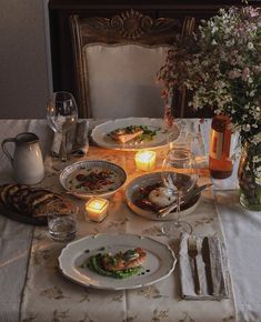 a dinner table set with plates, silverware and candles