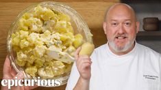 a man holding a potato in front of a bowl of potatoes