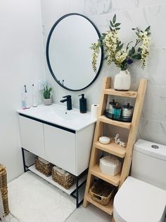 a bathroom with a white toilet, sink and shelf next to a round mirror on the wall