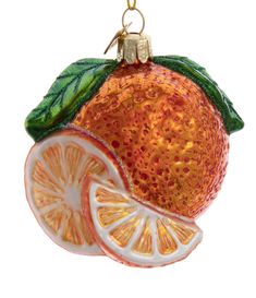 a glass ornament with an orange slice and green leaves on it's side