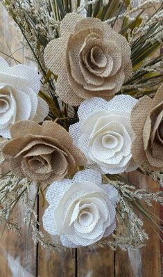 paper flowers are arranged in a vase on a wooden table with dried grass and twigs