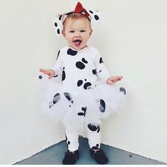 a baby dressed up in a dalmatian costume and holding her hands out to the side