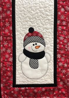 a quilted snowman with a black and white hat on it's head