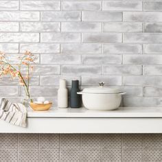 a white shelf with vases and bottles on it, next to a brick wall