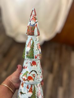 a hand holding a small christmas tree made out of fabric with santa clause on it