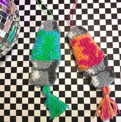 two crocheted items are on a checkered tablecloth with disco ball in the background