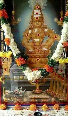 the statue is surrounded by flowers and garlands in front of an ornate wall decoration