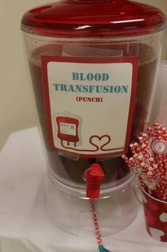 a plastic container filled with candy next to a cup full of candies and a sign that says blood transfusson punch