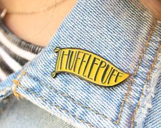 a yellow pin with the word tufflepuff on it sitting in someone's jeans pocket