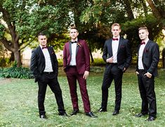 a group of men in tuxedos standing next to each other on a lush green field