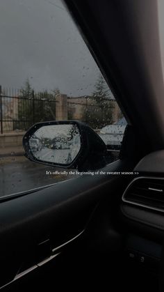 the side view mirror of a car on a rainy day