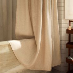 a bathroom with a bathtub and shower curtain in the corner, next to a chair