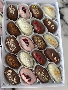 a box filled with assorted chocolates on top of a marble countertop next to a cupcake