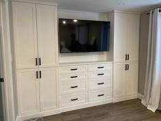 a room with white cabinets and a flat screen tv mounted to the side of it