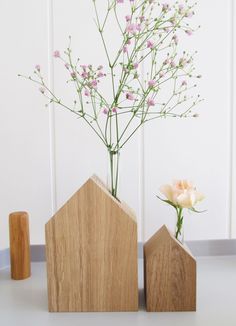 two vases with flowers in them sitting on a table next to a wooden block