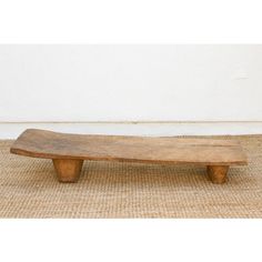 a wooden bench sitting on top of a rug next to a white wall and floor