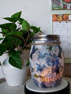 a jar sitting on top of a table next to a potted plant and calendar