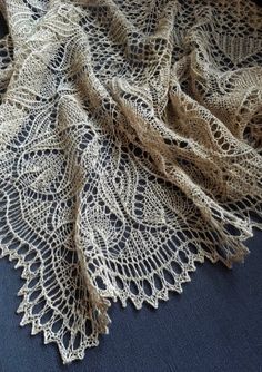 an old lace doily is laying on a blue tablecloth with white crochet