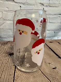 a glass with santa claus and snowflakes on it sitting on a wooden table