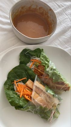 two lettuce wraps filled with meat and carrots on top of a white plate