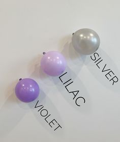 three balloons sitting on top of a white wall next to the words silver violet and silver