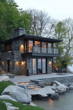 a large house sitting on top of a lush green hillside next to a lake with lots of trees