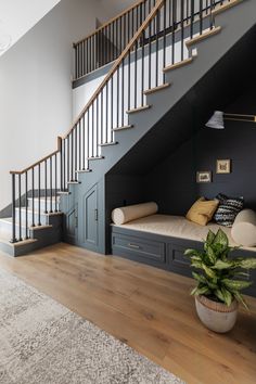 a living room with a couch under a stair case next to a potted plant