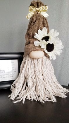 a stuffed doll is sitting on a table with some flowers in it's hair