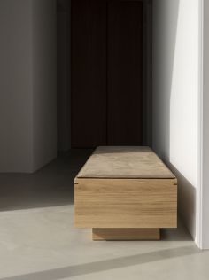 a wooden bench sitting in the middle of a room next to a wall and door