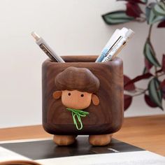 a small wooden cup with some pens and pencils in it