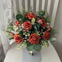 a vase filled with orange roses and greenery