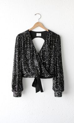 This long sleeve sequin top will make you look and feel powerful. It has a v-neckline and an open back. The shirt is secured with a tie in the back while cinching the waist. Fully lined. Sequin top Open back Long sleeves V-neck Satin tie Cuffed Lined Self: 100% Polyester Lining: 100% Polyester Length: 18" Chest: 17 1/4" Hand wash in cold water. Lay flat to dry. Model is wearing a size small Style #: G2210T6639