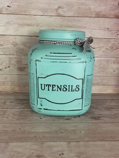 a blue jar with the word utensils on it sitting on a wooden floor