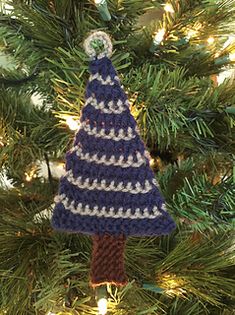 a crocheted christmas tree ornament hanging from a pine tree