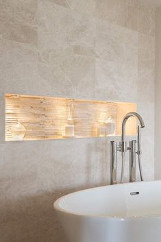 a white bath tub sitting in a bathroom next to a wall mounted shelf with candles on it