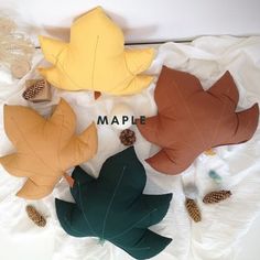 four different colored leaves laying on top of a white sheet with the word maple written below them