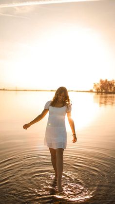 a woman standing in the water at sunset