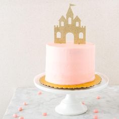 a pink and gold cake sitting on top of a table