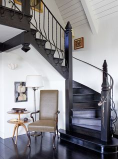 a chair sitting in front of a stair case on top of a hard wood floor