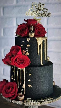 a black and gold wedding cake with red roses on the bottom tier, dripping in gold